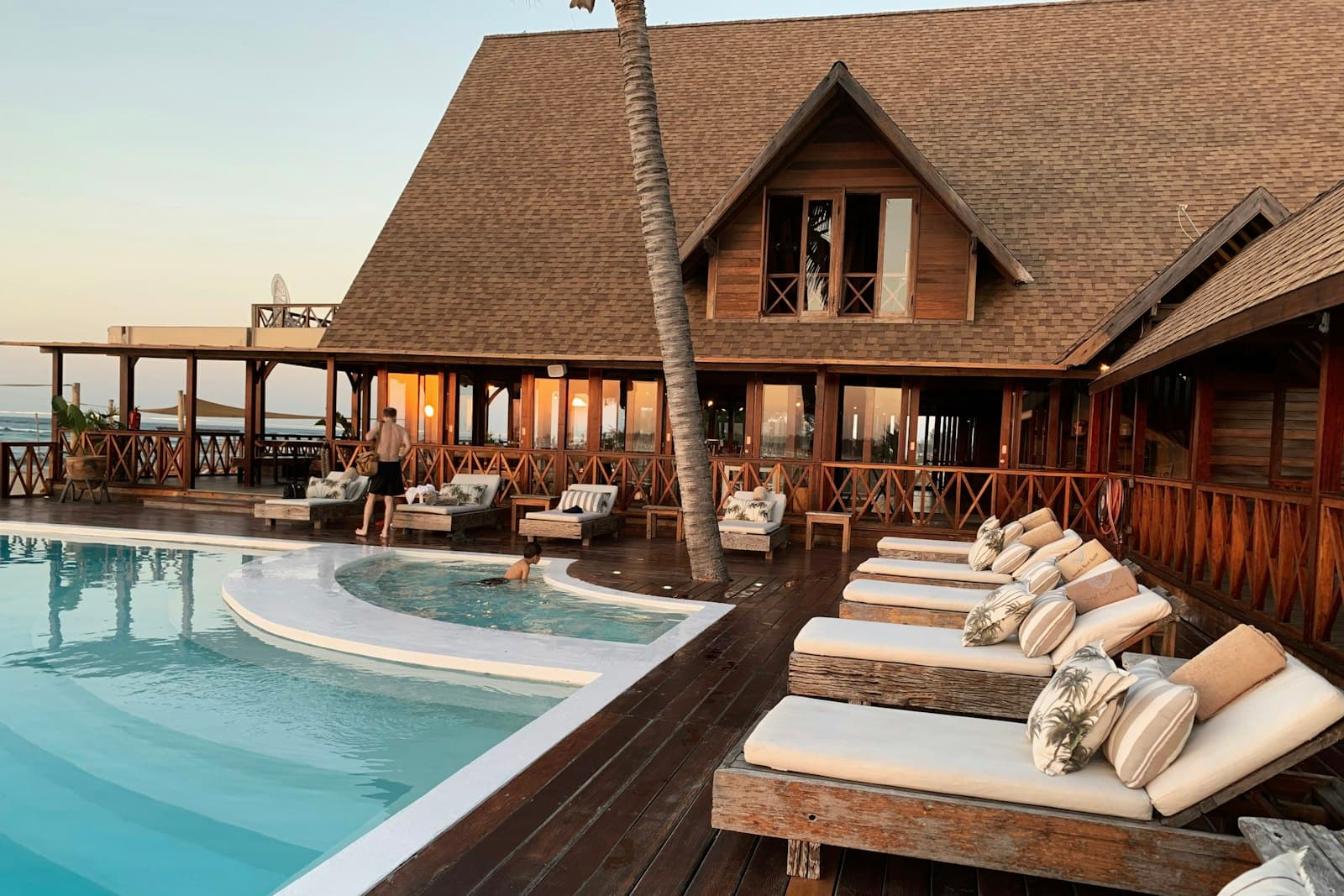Resort pool deck with sun loungers at sunset